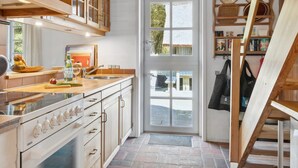 A kitchen with wooden cabinets, a stove, and a large window. - "Gravers" - 300m from the sea by Interhome (Læsø)