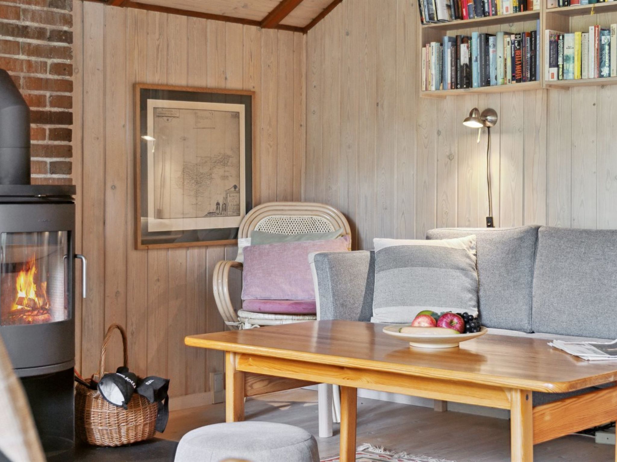 Ein gemütliches Wohnzimmer mit Kamin, einer Holzwand, einem Bücherregal und einer bequemen Sitzecke.