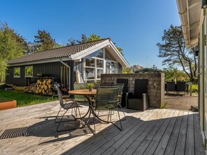 A wooden deck with outdoor furniture, a barbecue grill, and a stone fireplace. - "Tishon" - 100m from the sea by Interhome (Læsø)