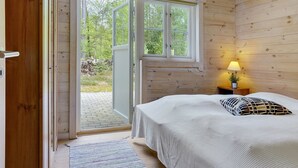 Een slaapkamer met een bed, nachtkastje, lamp en raam.