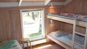 Una habitación pequeña y acogedora, amueblada con madera, con literas, una mesita y una ventana que proporciona luz natural.