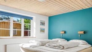 A bedroom with a bed, a window, and a blue wall. - "Tara" - 300m from the sea by Interhome (Læsø)