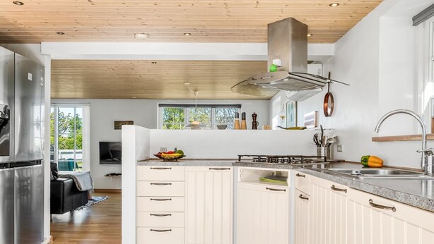 A modern kitchen with white cabinets, a stainless steel refrigerator, and a wooden ceiling. - "Tara" - 300m from the sea by Interhome (Læsø)