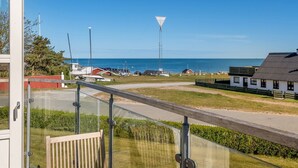 A coastal view with a clear sky, a lighthouse, and a road leading to a white building with a black roof. - "Tara" - 300m from the sea by Interhome (Læsø)