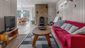 A living room with a TV, red sofa, fireplace, and a dining area with chairs.