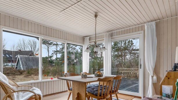 A room with a wooden table, chairs, a window, and a view of the outside.