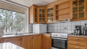 A kitchen with wooden cabinets, a white refrigerator, a stove, and a coffee maker.