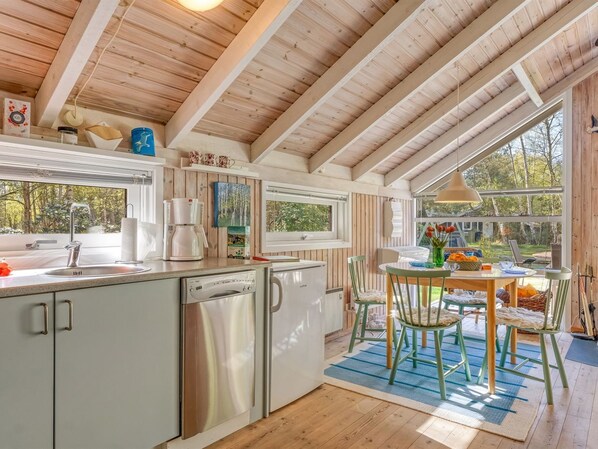 A kitchen with a dishwasher, a coffee maker, and a window overlooking a garden.