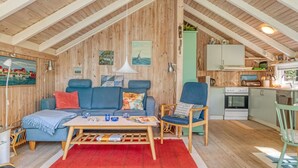 Ein gemütliches Loft-Zimmer mit hohen Decken, Holzwänden, einem blauen Sofa, einem Holztisch und einer Küchenzeile mit Herd und Spüle.