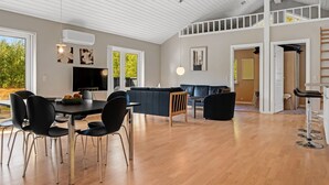 Un grand espace de vie comprenant une table à manger, des chaises, un canapé et un téléviseur.