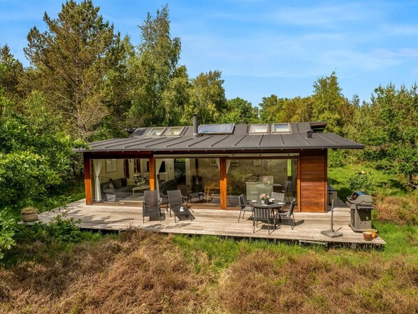 A modern house with a deck, glass doors, and a solar panel.