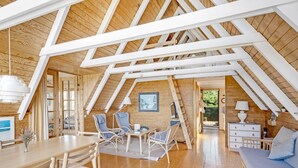 Ein gemütliches, hölzernes Interieur mit Essbereich, Sitzgelegenheiten und einer Couch.