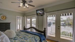 Une chambre à coucher avec un lit, un ventilateur de plafond, une horloge et un téléviseur.