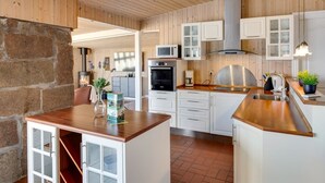Una cocina moderna con paneles de madera, una pared de piedra y una isla integrada con pileta.