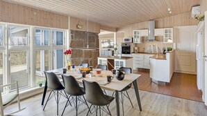 Una cocina moderna con armarios blancos, una pared de piedra y un comedor con mesa y sillas.