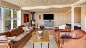 Amplia sala de estar con chimenea, sofás de cuero, una mesa de centro y un televisor.