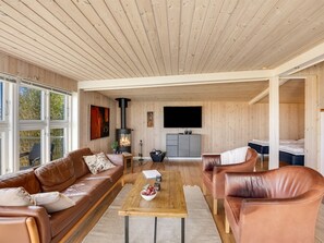 A spacious living area with a fireplace, leather sofas, a coffee table, and a TV.