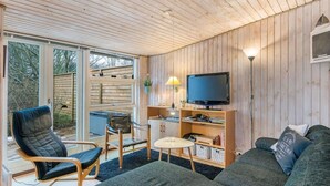 Una sala de estar acogedora con un sofá, un sillón, una mesita y un televisor.