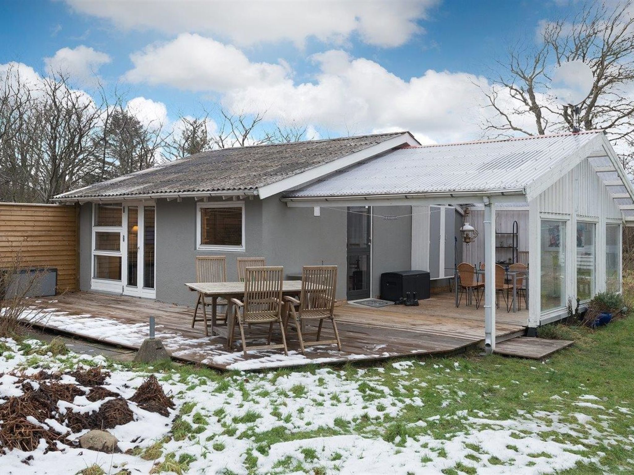 Une maison dotée d’un patio, d’un espace extérieur couvert et d’un jardin où l’on peut encore apercevoir des plaques de neige.