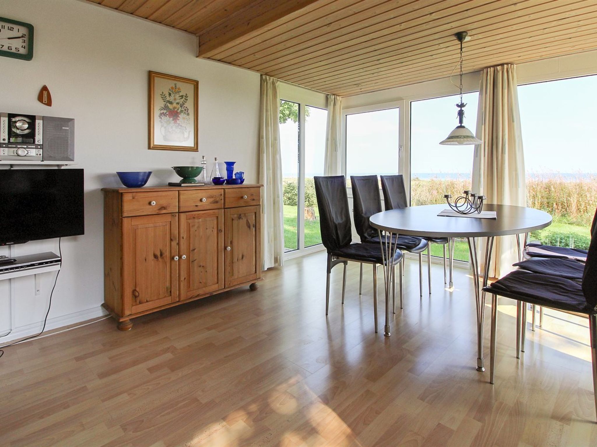 A modern kitchen with wooden cabinets, a dining table with chairs, and a television.
