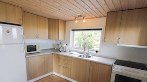 A modern kitchen with wooden cabinets, a microwave, a coffee maker, a sink, and an oven.