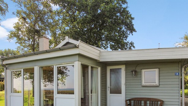 A house with a covered porch, a bench, and a number 14 sign.