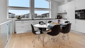 Een moderne keuken met witte kastjes, een ronde eettafel en zwarte stoelen.