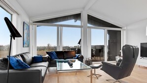 Een moderne woonkamer met een glazen salontafel, een leren bank en een zwarte fauteuil.