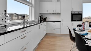 Een moderne keuken met witte kasten, een zwart aanrecht en uitzicht op het buiten.