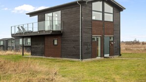 Een modern huis met twee verdiepingen, een balkon, grote ramen en een plat dak.