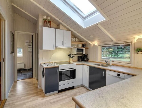 Enjoy cooking in this kitchen with a skylight, white cabinetry, and large window offering a view of the outdoors.