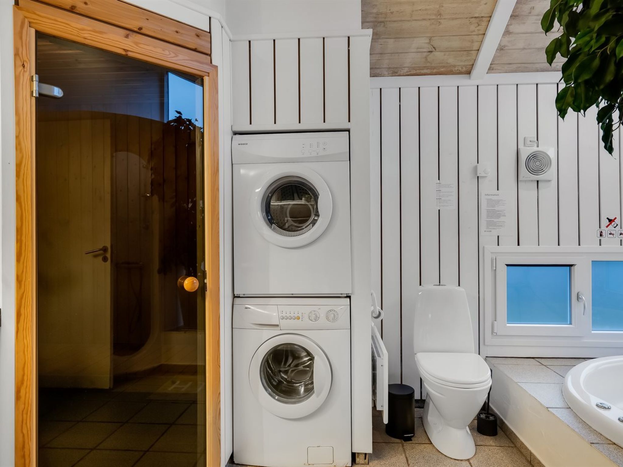 A compact, modern bathroom with a built-in washer and dryer, a toilet, and a bathtub.