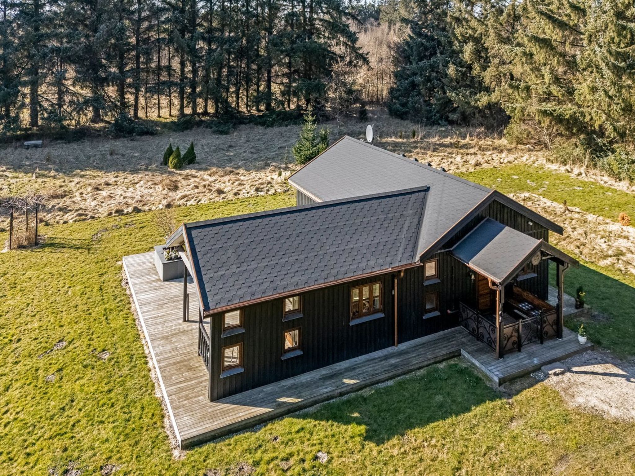 A modern log cabin with a large deck and a covered porch.