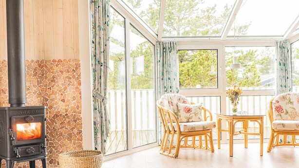 A cozy room with a wood-burning stove, wicker basket, wicker chairs, and a view through large windows. - "Mila" - 750m from the sea by Interhome (Bindslev)