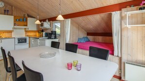 A compact kitchen with modern appliances, a dining area with a white table and chairs, and a cozy sleeping area with a bed and curtains. - "Menka" - 1.3km from the sea by Interhome (Bindslev)