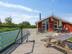 Un edificio rojo con terraza, asientos exteriores y una mesa de picnic.