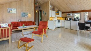 A spacious living area with a wooden ceiling, a red sofa, a rocking chair, and a kitchen area with white cabinets and a microwave. - "Menka" - 1.3km from the sea by Interhome (Bindslev)