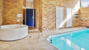 A modern indoor pool area with a brick wall, a hot tub, and a door. - "Riika" - 425m from the sea by Interhome (Hirtshals)