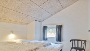 A bedroom with a bed, a chair, a window with curtains, and a wall-mounted light fixture. - "Riika" - 425m from the sea by Interhome (Hirtshals)