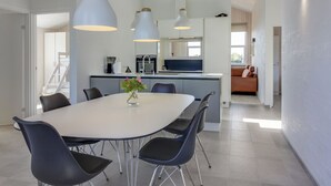 Une cuisine moderne dotée d’un îlot central, de luminaires suspendus et d’un coin repas avec une table ronde et des chaises.