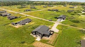 Vue aérienne d’un quartier résidentiel avec de nombreuses maisons, des routes et des champs verdoyants.