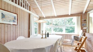 Un comedor con una mesa redonda, sillas blancas y una pared de ladrillo.