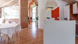 Una cocina amplia con un pilar de ladrillo, encimeras blancas y una pared de acento roja.