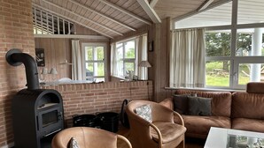 Una sala de estar acogedora con chimenea de ladrillo, sofás de cuero y amplios ventanales con vistas al exterior.
