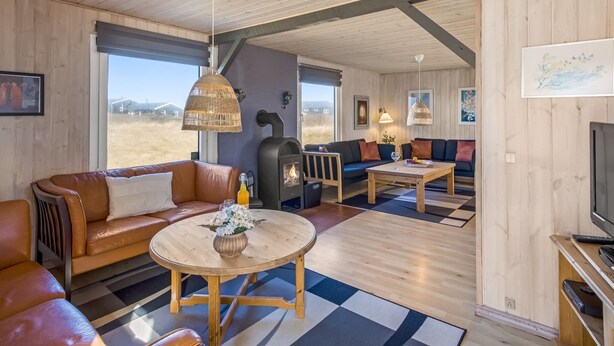 Ein gemütliches Interieur mit Kamin, Ledersofa, rundem Holztisch und Fernseher.
