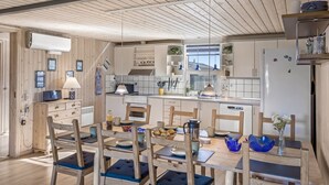 Eine moderne Küche mit Holzschränken, einer zentralen Kochinsel und einem Essbereich mit Stühlen und Tisch.