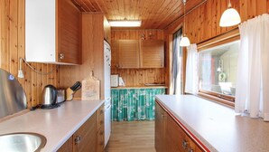 A compact kitchen with wooden cabinets, a sink, and a window with curtains.