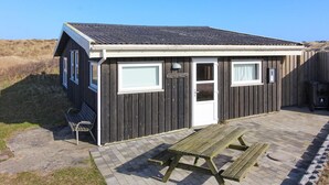 A small wooden building with a white door and windows, a picnic table, and a sign that reads "RUTHS HUS".