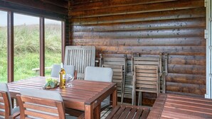 Eine Holzhütte mit Esstisch und Stühlen, einer Weinflasche und einem Glas.