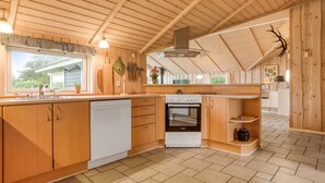 Een houten interieur met een keukenhoek, inclusief een spoelbak, fornuis en oven.